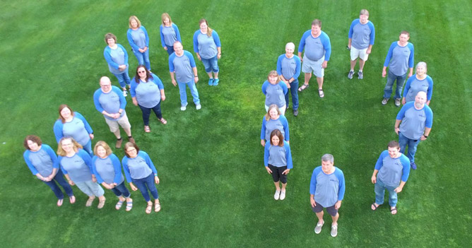 EMB team photo showing members forming the shape "20" captured by drone above.
